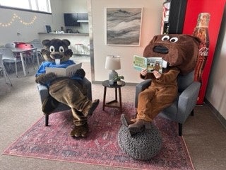 people in beaver costumes sitting and reading books.
